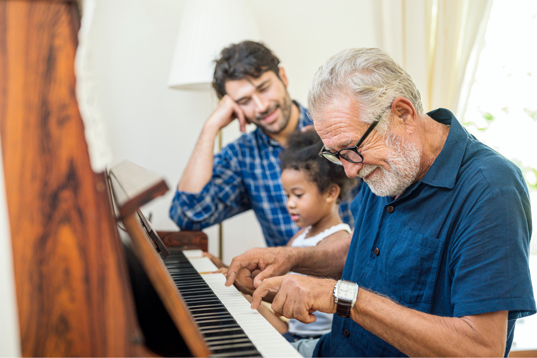 Smiling 55+ man with a child and a younger man at a piano